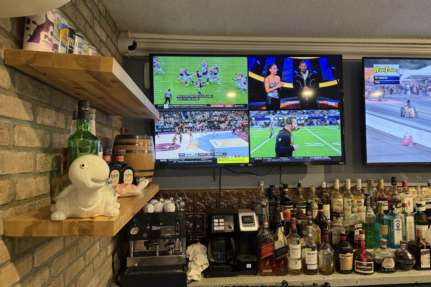 The bar with screens above the bottles and a turtle on the shelf.