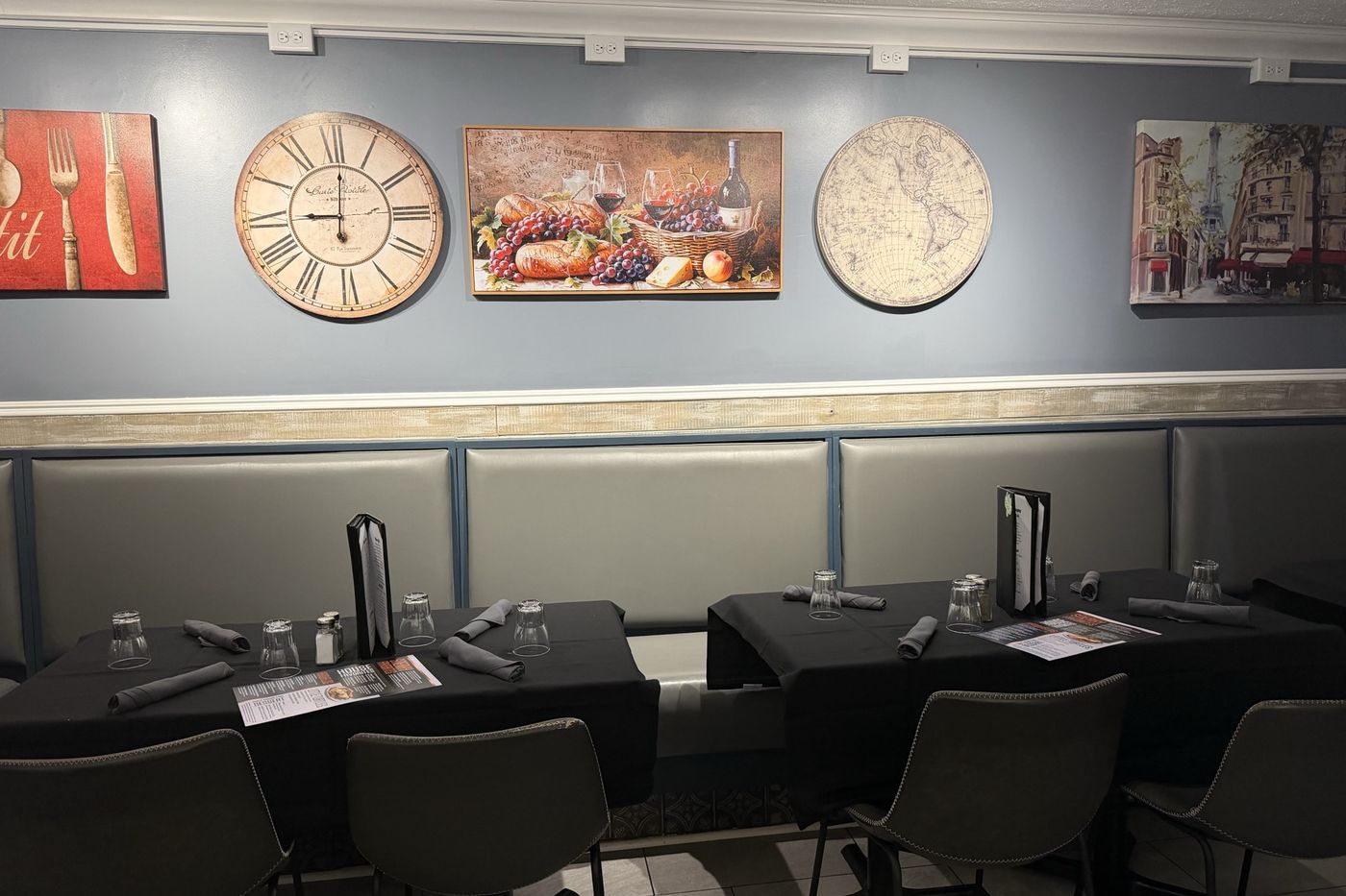 The booth wall hung with a clock, a still life and a Paris street scene.